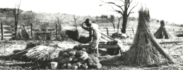 Unknown African American male breaking hemp on hand brakes in a field of hemp stalk stacks